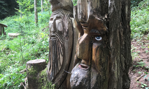 Mit Kettensägen in Holz geschnitzte Schauergestalten grüßen den Wanderer.